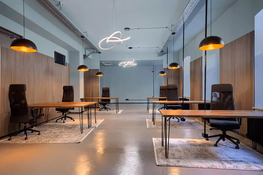 Stilvolles Bürointerieur mit Holztischen, schwarzen Stühlen und künstlerischen Leuchten, nach Renovierung in München.