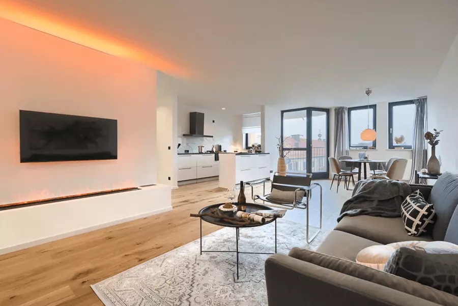 Offener Wohnraum mit elegantem Kamin, stilvoller Einrichtung und Holzboden in einem frisch renovierten Apartment in München.