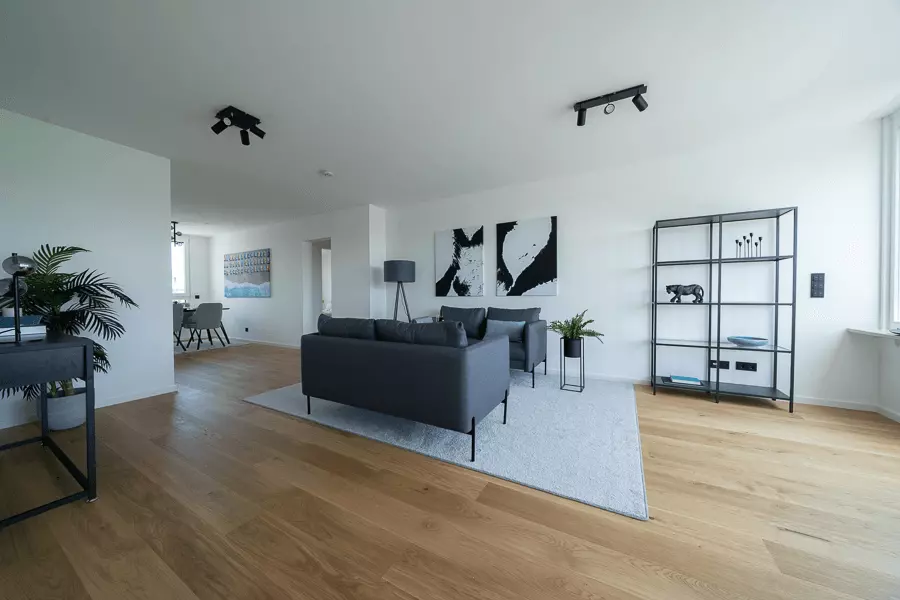 Luftiges Wohnzimmer mit modernen Möbeln, abstrakter Wandkunst und natürlichem Licht in einer eleganten Münchner Wohnung.