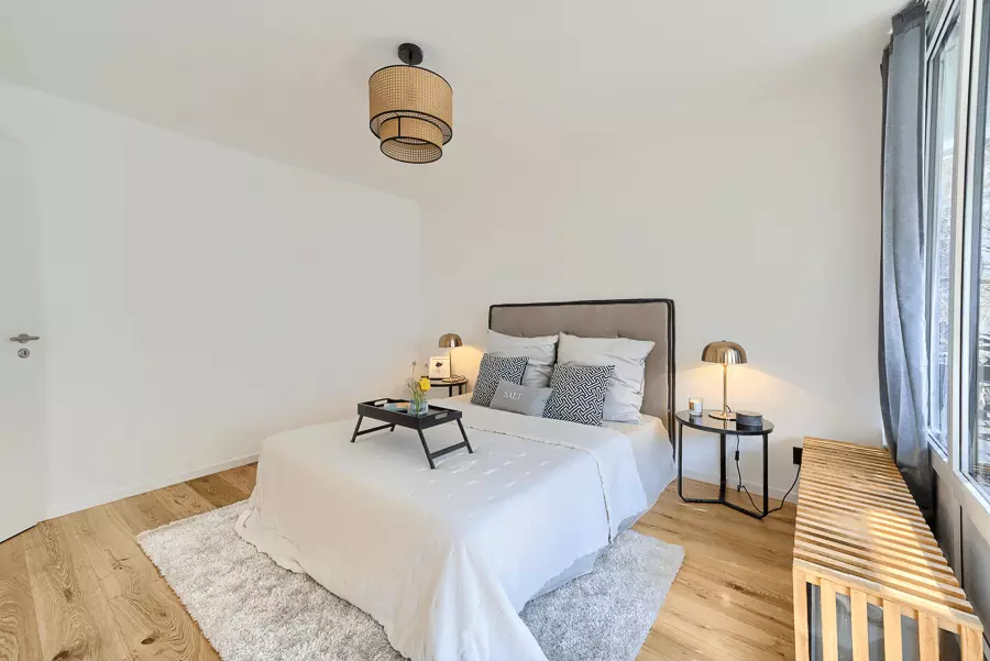 Elegantes Schlafzimmer mit Eichenparkett, maßgefertigtem Bettgestell und dezentem Beleuchtungskonzept in einer Münchner Wohnung.