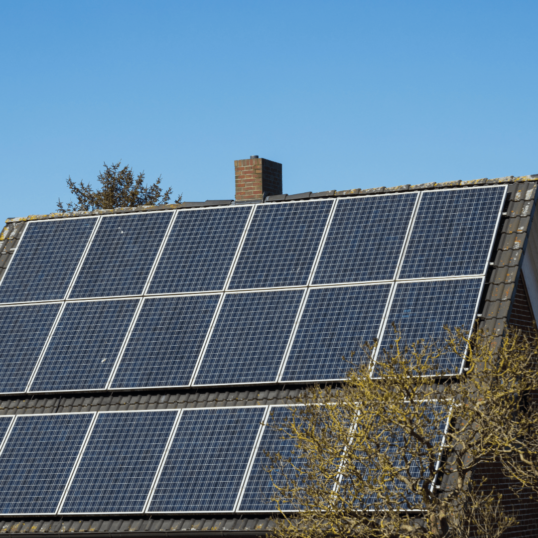 Photovoltaik-Paneele auf dem Dach eines renovierten Münchner Wohnhauses, Symbol für umweltfreundliche Sanierung